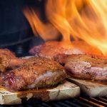 Op een plank gegaarde eendenbouten met vuur op de barbecue
