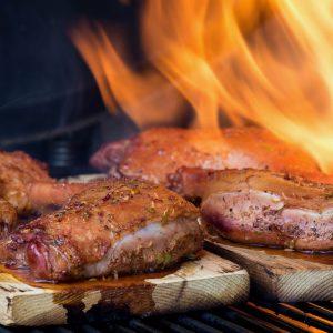 Op een plank gegaarde eendenbouten met vuur op de barbecue